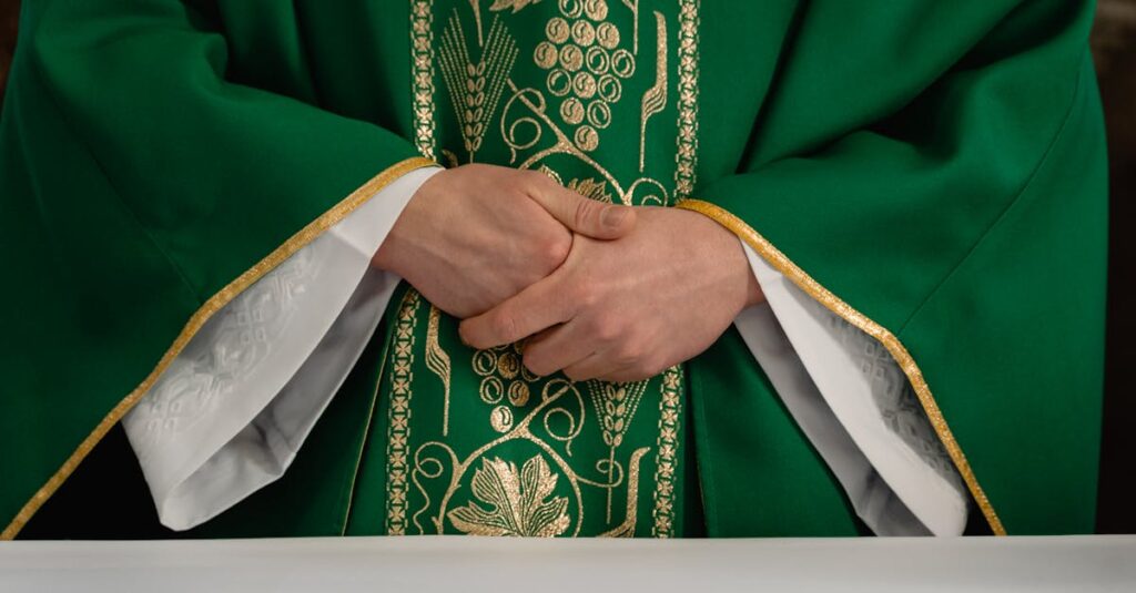 pexels-photo-7219528-7219528 A close-up view of a priest's hands clasped in prayer wearing a green chasuble with gold embroidery.